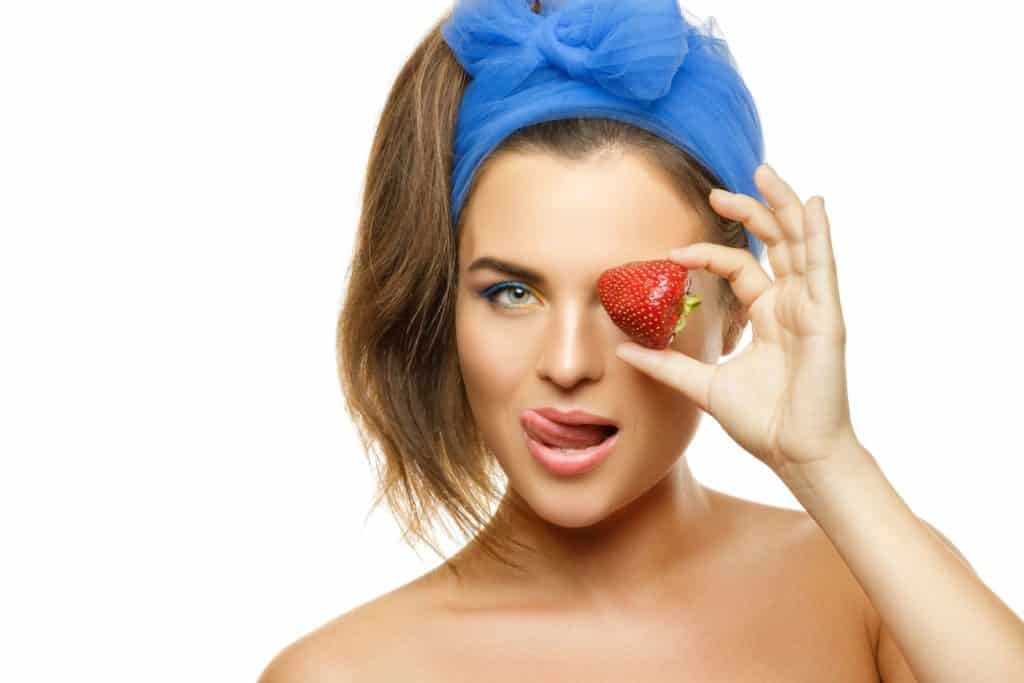 Beautiful woman with colorful makeup and strawberry