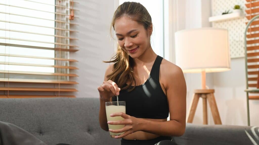 Attractive woman drinking collagen supplement